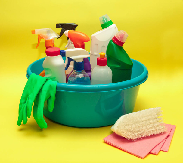 Set of cleaning products and detergents in a blue basin, on a yellow background. Cleaning, disinfection. Sanitation. Space for text. - Fotografie, Obrázek