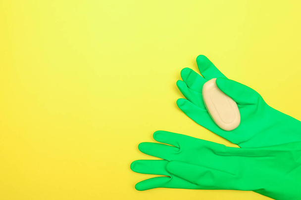 Het begrip reinheid en hygiëne. Zeep in rubberen handschoenen op een gele achtergrond. Desinfectie. Ruimte voor tekst, platte lay. - Foto, afbeelding