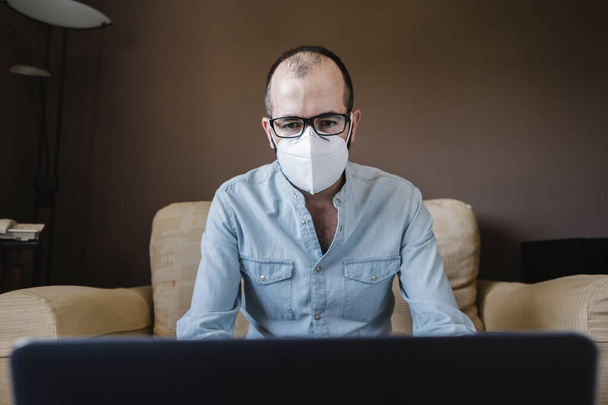 自宅からリモートで作業白いマスクで病気のビジネスマン。新しい標準概念における電気通信 - 写真・画像