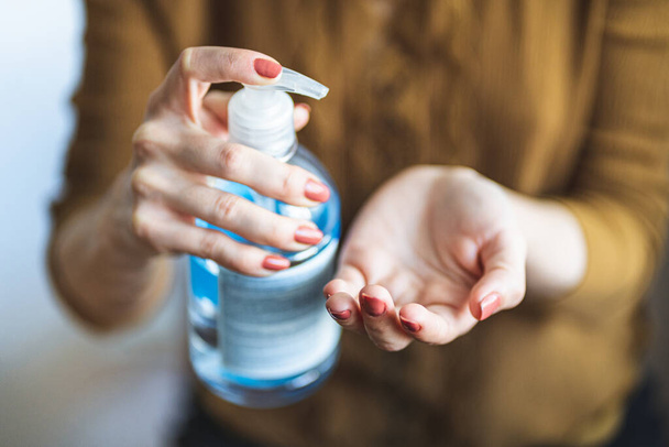 Close up female hands using wash hand sanitizer gel pump dispenser during coronavirus epidemic outbreak. Washing hand with hand sanitizer to avoid contaminating with Coronavirus. Disinfection concept - Photo, Image