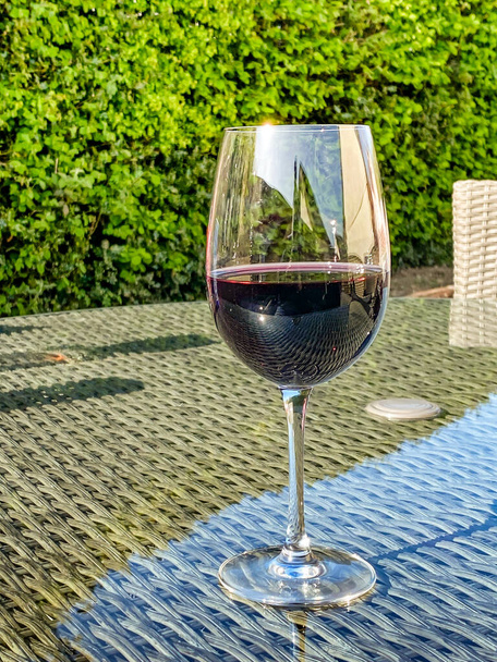 Bicchiere di vino rosso sul tavolo di vetro superiore dei mobili da giardino, Nessuna gente, Copia spazio
. - Foto, immagini