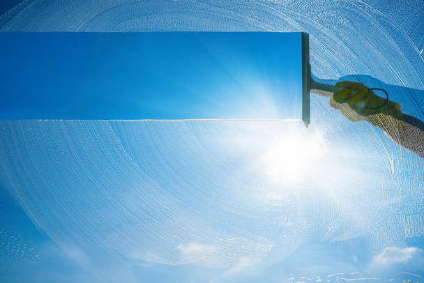 Raamreiniger met ruitenwisser en ruitenwisser op een zonnige dag met een helderblauwe lucht. - Foto, afbeelding