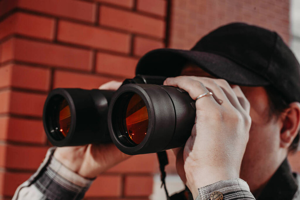 vousatý muž se dívá dalekohledem do města - Fotografie, Obrázek