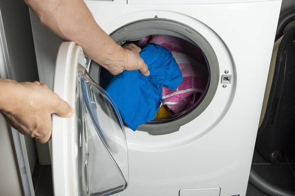 Widok z bliska męskiego układania prania w pralce. Rutynowa koncepcja domu - Zdjęcie, obraz