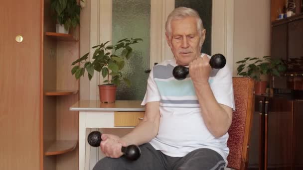 Ανώτερος ηλικιωμένος καυκάσιος άνδρας που κάνει ασκήσεις ανύψωσης βάρους αλτήρα στο σπίτι - Πλάνα, βίντεο