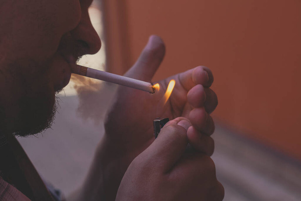 чоловік запалює цигарку ввечері
 - Фото, зображення