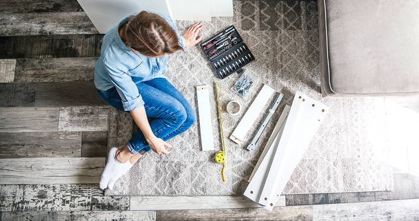 Young woman assembling new furniture for home - Foto, imagen