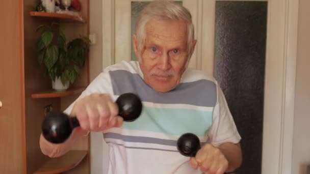 Senior anciano caucásico hombre haciendo ejercicios deportivos con mancuernas en casa
 - Metraje, vídeo