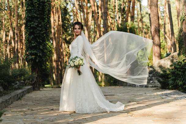 cute bride holds a bouquet in a beautiful wedding dress,happy bride,bride fluttering veil - Foto, Imagem