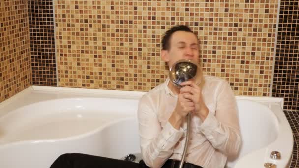 Мужчина в рубашке и брюках в ванне с водой поет
 - Кадры, видео
