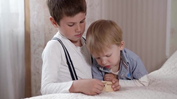 schöne fröhliche attraktive Junge spielen mit seinem kleinen Bruder genießen Sie spielen in Spieluhr Melodie hören - Filmmaterial, Video