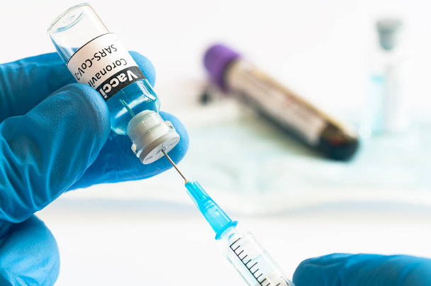 Coronavirus COVID-19 vakcinát tartalmazó injekciós üveg és injekciós fecskendő orvosi kézben - Fotó, kép