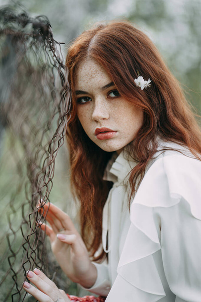 red-haired girl with freckles in cherry blossom. - Foto, Imagem
