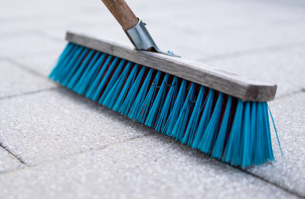 detalle del pincel azul utilizado para la limpieza del pavimento hecho de piedras de hormigón
 - Foto, Imagen