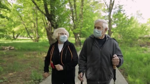 Active senior old man, woman training Nordic walking in park during quarantine - Footage, Video