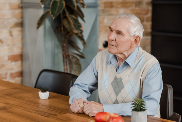 senior lonely man with fruits and plants on table during self isolation  - Foto, afbeelding