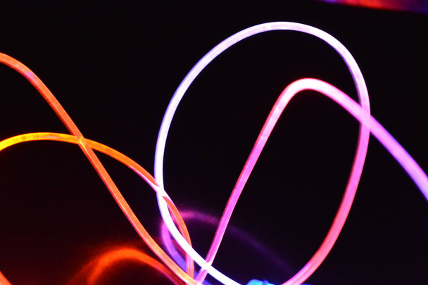 Fil lumineux orange et bleu, fil de guidage lumineux avec différentes transmissions de lumière, spectre lumineux et effets de lumière situés dans un état chaotique avec réflexion de la lumière sur un fond noir brillant
. - Photo, image
