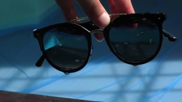 Víz csöpög a napszemüveg a medence oldalán és hullámok alatt. - Felvétel, videó