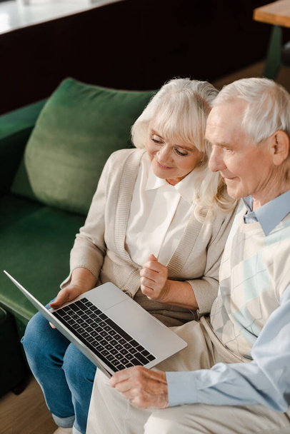 smiling senior couple using laptop at home during self isolation - Фото, зображення