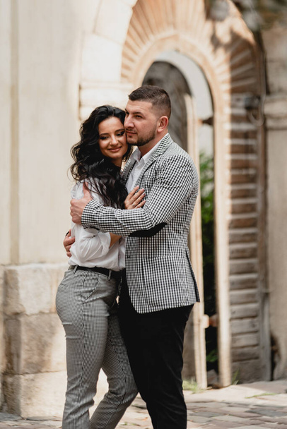stylish middle-aged couple gently hugging on the streets of the old city,the guy gently kisses the girl,cellular clothing - Fotoğraf, Görsel