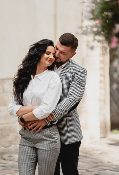 stylish middle-aged couple gently hugging on the streets of the old city,the guy gently kisses the girl,cellular clothing - Photo, Image
