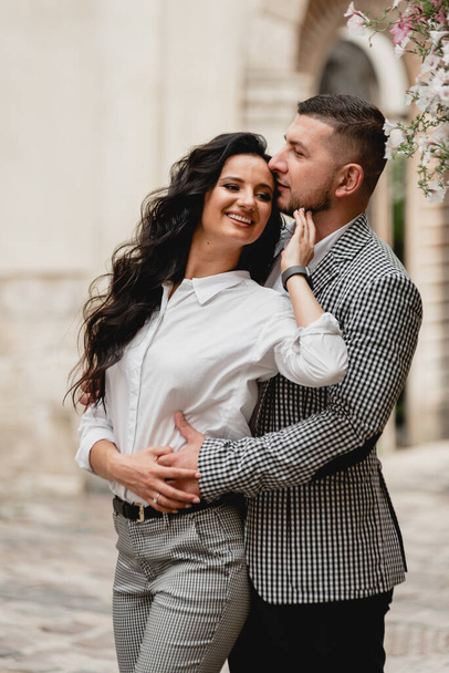stylish middle-aged couple gently hugging on the streets of the old city,the guy gently kisses the girl,cellular clothing - Fotografie, Obrázek