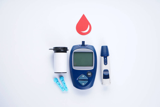 Diyabet. Beyaz arka planda izole edilmiş kan şekeri seviyelerini belirlemek için elektronik glukometre, neşter ve test şeridi.. - Fotoğraf, Görsel