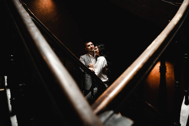 couple standing in the shade on the stairs,couple standing on a dark background where the light shines from above - Foto, Bild
