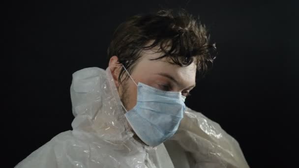 vermoeide zwetende arts doet pak uit en masker haalt diep adem en sluit de ogen aan het einde van de werkdag in de strijd tegen het coronavirus in het ziekenhuis - Video