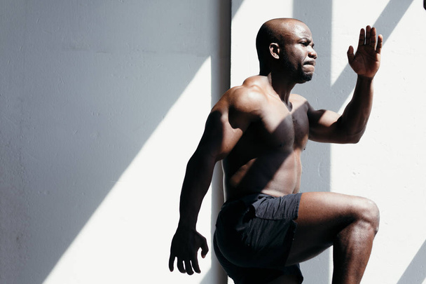 Fitness trainer is warming up before the race. Relief muscles of a black man in the sunlight - Valokuva, kuva