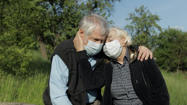 Coppia anziana in maschere mediche durante la quarantena del coronavirus COVID-19 nel parco
 - Foto, immagini