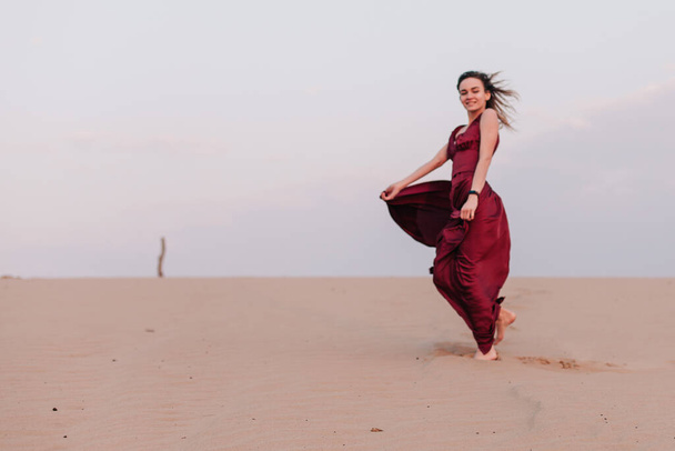 Girl in red dress with cloth in the wind in the desert - Fotografie, Obrázek