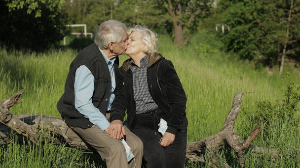 Senioren-Großelternpaar im Park während covid-19 Coronavirus. Einen Kuss machen - Foto, Bild