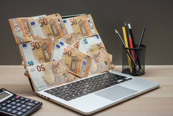 open laptop met scherm bedekt met eurobankbiljetten - Foto, afbeelding