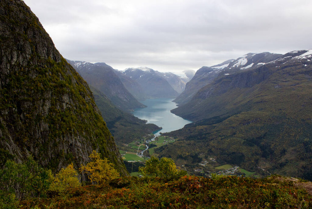 Vadi ve Lovatnet 'in manzarası Norveç' in Loen kentindeki Ferrata 'nın yakınlarındaki bir dağın arka planında dağlar var. Ekim sabahı ağır bulut örtüsü, Norveç açık hava güzelliği. - Fotoğraf, Görsel