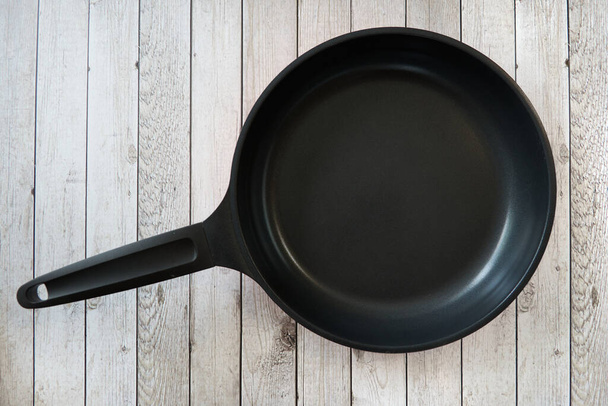 Empty pan on a kitchen table.Empty pan on a kitchen table on wooden culinary background. Top view. - Foto, imagen