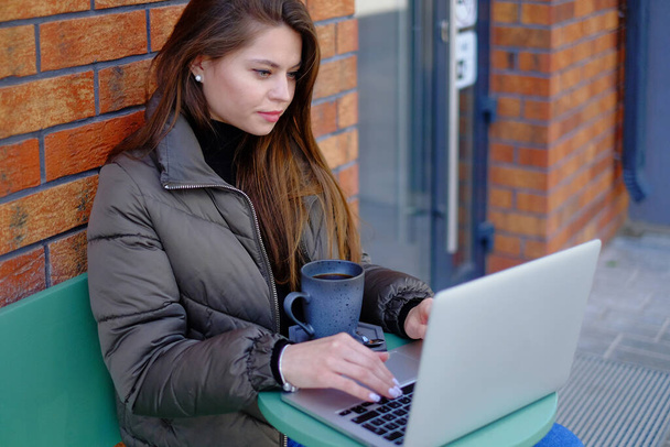 Όμορφη γυναίκα hipster χρησιμοποιώντας φορητό υπολογιστή στο καφέ, ενώ πίνοντας καφέ χαλαρωτικές διακοπές έννοια. - Φωτογραφία, εικόνα