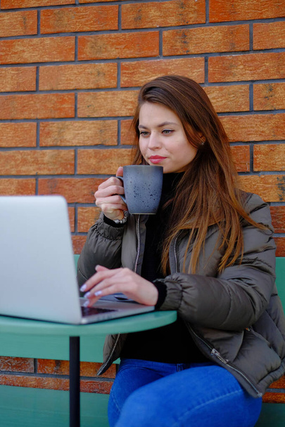 Beautiful hipster woman using laptop at cafe while drinking coffee relaxing holiday concept. - Foto, Imagem
