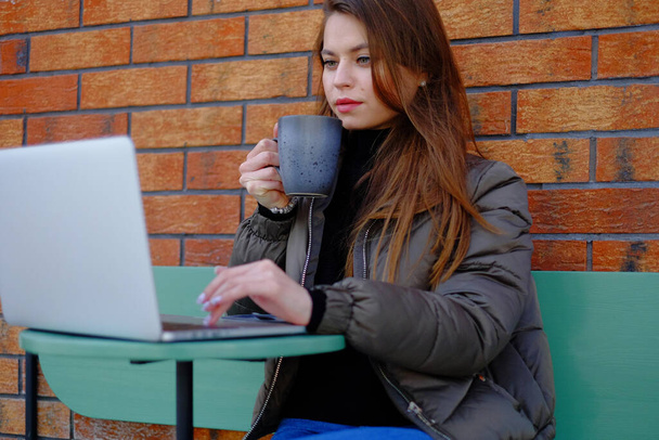 Hermosa mujer hipster utilizando el ordenador portátil en la cafetería mientras bebe café relajante concepto de vacaciones
. - Foto, Imagen
