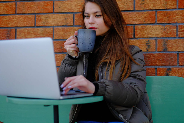 Beautiful hipster woman using laptop at cafe while drinking coffee relaxing holiday concept. - Foto, afbeelding