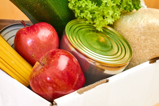 箱にりんご、缶詰、米などの野菜を閉じます。フードデリバリーサービス.  - 写真・画像