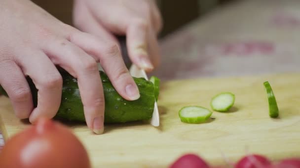 Naaraskokki leikkaa tuoreita vihanneksia. Nainen, joka käyttää keittiöveistä tuoreen kurkun leikkaamiseen
 - Materiaali, video
