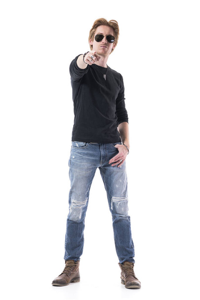 Cool confident stylish young man with sunglasses looking at pointing finger at you. Full body length isolated on white background.  - Foto, afbeelding