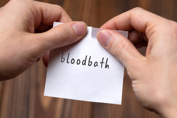 Mãos arrancando papel com inscrição banho de sangue
 - Foto, Imagem