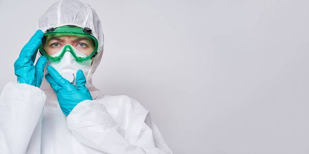 Doctor draagt PPE - kostuum, handschoenen en chirurgische gezichtsmasker. - Foto, afbeelding