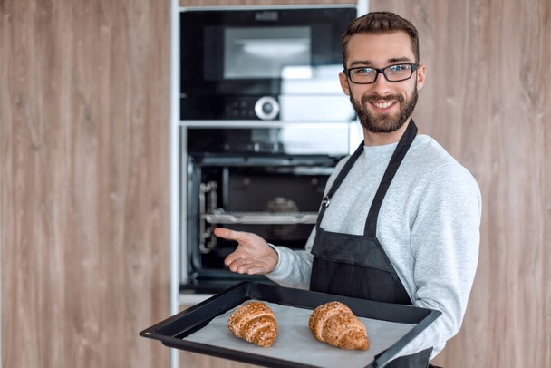 smiling man holding a tray of fresh croissants - Fotoğraf, Görsel