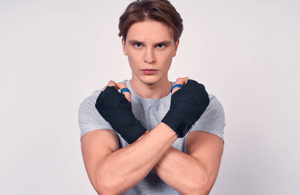 Young lovely fitness sporty guy 20s athlete in headband t-shirt spend weekend in home gym isolated on white background. Training sports motivation concept. Boxing with sports bandages on his hands. - Fotoğraf, Görsel