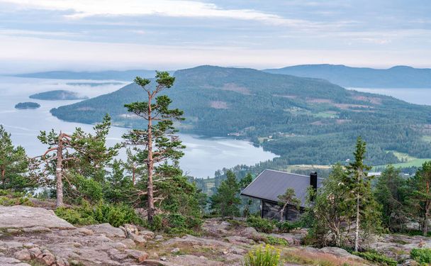 Maison de repos touristique publique en face de la vue sur les montagnes scandinaves avec forêt de pins, le village et deux baies maritimes, journée d'été avec de lourds nuages dramatiques, Suède du Nord
 - Photo, image