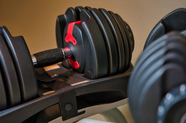 Dumbbells sitting on rack. Adjustable bowflex weights on stand. - Photo, image