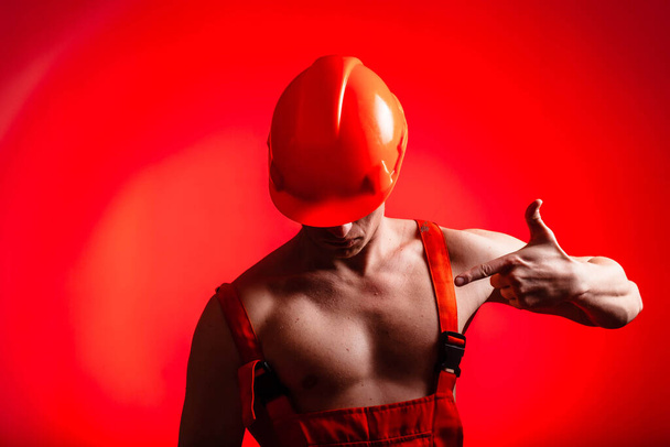 Сексуальный строитель на красном фоне. Строитель со шлемом на голове. Сексуальный строитель. Насосные руки и спина
. - Фото, изображение